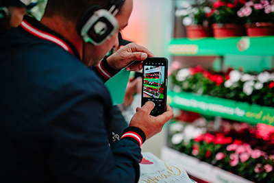 Man taking a photo of a flower cart with his phone