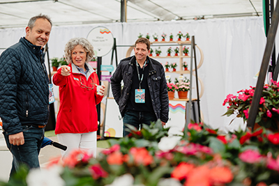 Woman with a red jacket talking to two men about flowers