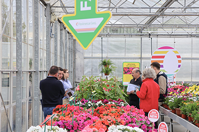 Group of people in a greenhouse filled with an assortment of colorful plants
