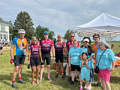 Bike riders and volunteers near a tent outdoors