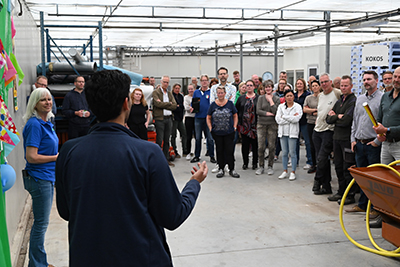 A man talking in front of a crowd in a warehouse