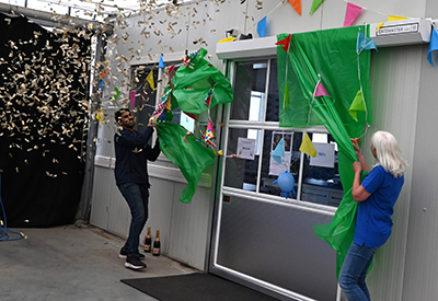 Two people unveiling a grand opening with confetti