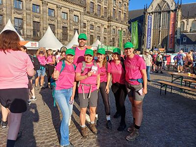 Group of happy people in pink shirts standing outside