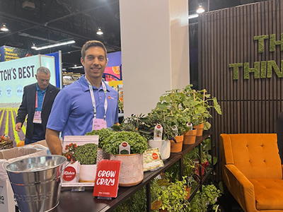 Dylan Sedmak from PanAmerican Seed stands at a trade show booth featuring Kitchen Minis plants.