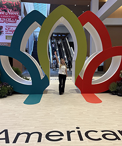 Woman waving her hand in front of the Cultivate'26 tradeshow display