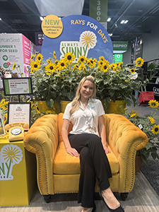 Woman sitting on a yellow velvet chair surrounded by sunflowers