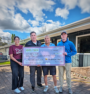 Team of people present a charitably check during an outdoor event.